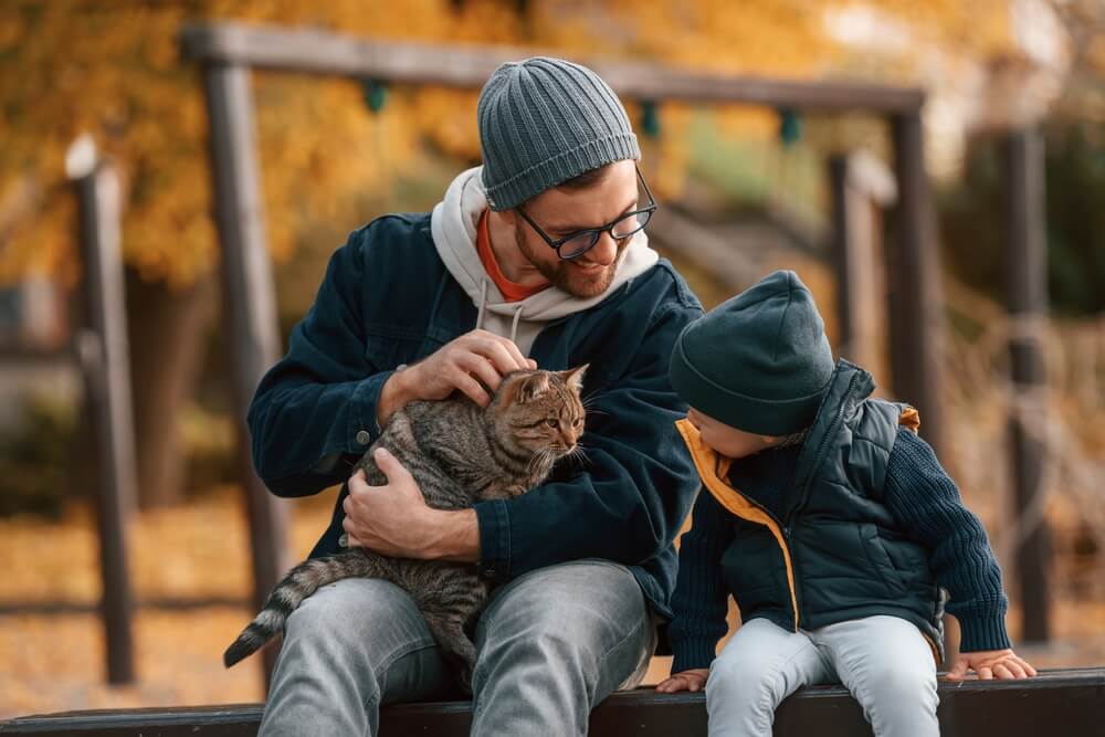 Dad and son with pet cat at park