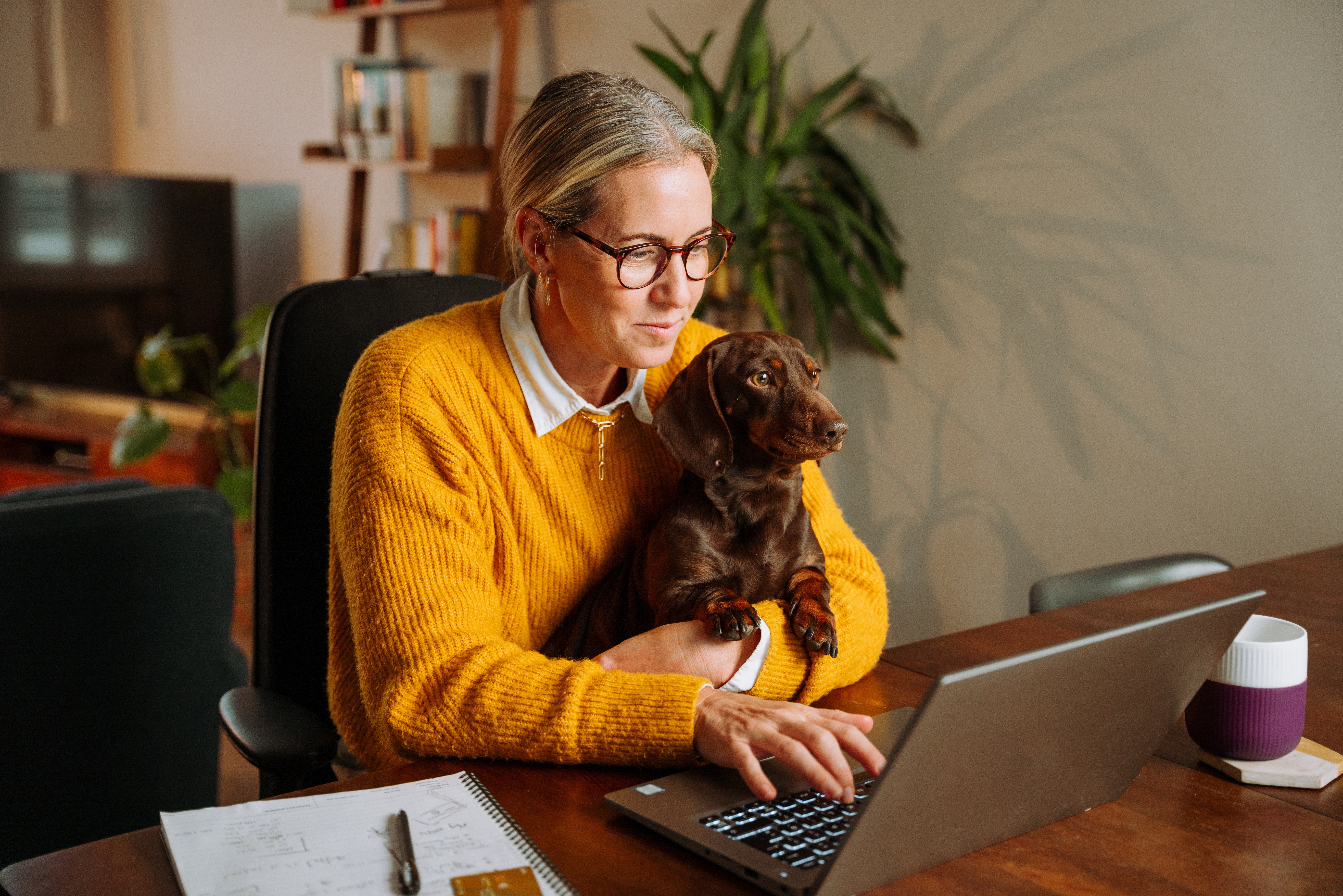 assignee working on laptop with pet dog
